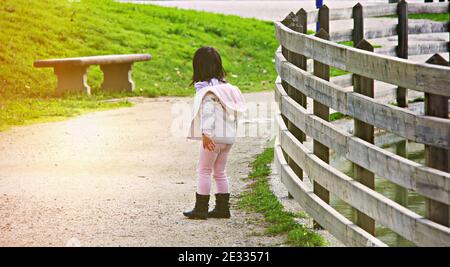 vue arrière d'un adorable enfant asiatique jouant dans le parc, regardant une lumière, un concept d'enfance, rêvant et croyant Banque D'Images