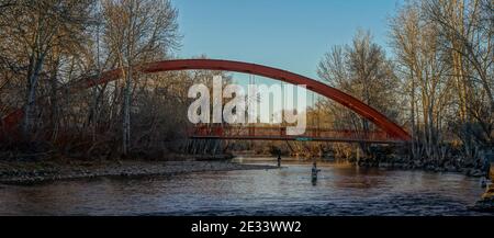 Deux hommes pêchent dans la rivière Boise de l'Idaho, sous le pont piétonnier Baybrook court, un après-midi d'hiver. ÉTATS-UNIS Banque D'Images