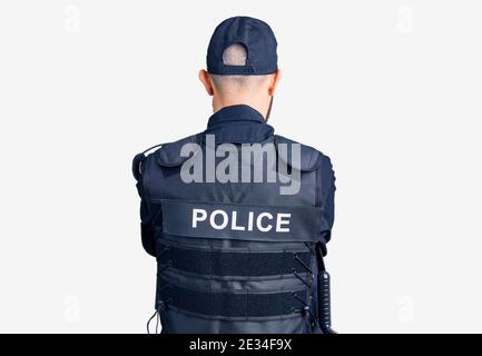 Jeune homme beau portant l'uniforme de police debout en arrière en regardant loin avec bras croisés Banque D'Images