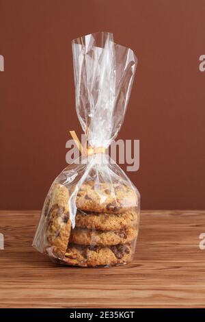 Biscuits aux flocons d'avoine avec noix et raisins secs dans un sac transparent sur une table en bois. Gros plan Banque D'Images