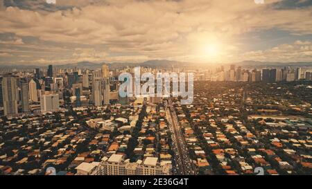 Paysage urbain de Sun City à l'antenne du centre-ville. La lumière du soleil dans les rues et les routes avec des bâtiments de bloc. Gratte-ciels modernes dans le centre d'affaires de Manille, Philippines. Vue cinématique de drone Banque D'Images