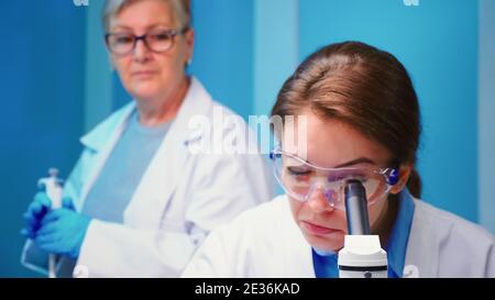 Gros plan de la chimiste femme médecin travaillant dans un laboratoire scientifique équipé à l'aide d'un microscope. Un scientifique analysant diverses bactéries, des échantillons de sang de tissus faisant de la recherche pharmaceutique pour les antibiotiques Banque D'Images