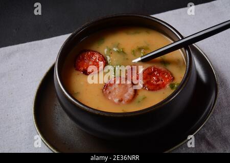 Soupe de Caldo Verde aux légumes verts et chorizo haché sur le dessus du bol sur fond sombre. Banque D'Images