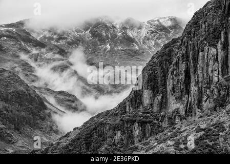 Superbe image de paysage d'hiver en noir et blanc à partir de Pike latéral vers Langdale pikes avec nuages bas niveau sommets de montagne et brume de moody Banque D'Images