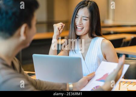 Vue arrière de Boss félicitant la femme d'affaires asiatique en action heureuse quand le projet réussi ou obtenir la promotion, récompensant l'objectif d'affaires en Mo Banque D'Images