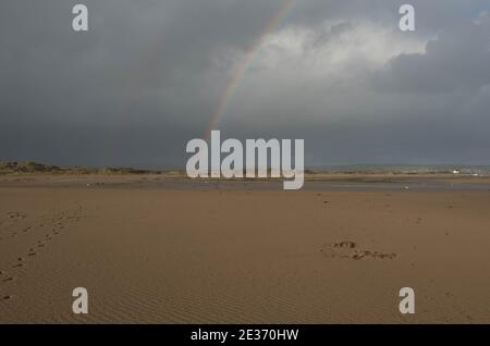 Ciel hivernal orageux avec arc-en-ciel au-dessus des dunes de sable à Crow point par Braunnton Burrows sur la côte nord à Devon, Angleterre, Royaume-Uni Banque D'Images
