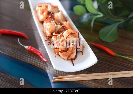 Mise au point sélective de crevettes grillées avec oignons et piment sur une assiette blanche sur la table. Pour un menu asiatique Banque D'Images