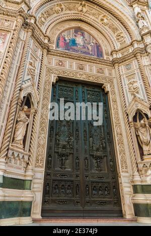 Grande vue rapprochée des immenses portes en bronze de la cathédrale de Florence sur le portail central et une lunette au-dessus avec une mosaïque colorée de Christ enthroned... Banque D'Images