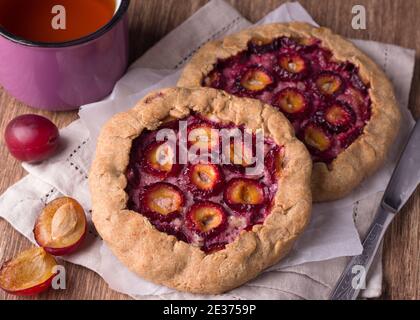 Mini-tartes vegan maison avec noix et prunes fraîches sur une table en bois, vue sur le dessus Banque D'Images