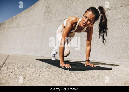 Femme en bonne santé faisant de l'exercice alpinistes. Femme de sport s'exerçant sur un tapis à l'extérieur. Banque D'Images