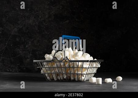 Guimauves aérées blanches dans un panier d'épicerie sur un sombre arrière-plan en bas de la clé Banque D'Images
