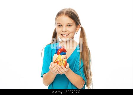 Fille tenant un modèle anatomique de coeur dans les mains. Concept de santé cardiaque et diagnostic de la maladie cardiaque des enfants Banque D'Images