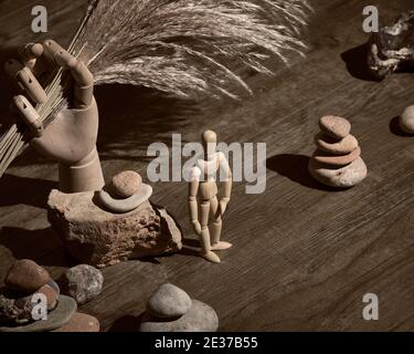 Modèle en bois tenant à la main sec avec l'herbe de pampas. Figure humaine aux pyramides de pierre zen. Trouver l'équilibre intérieur en direct. Vintage, rétro grunge arrang Banque D'Images