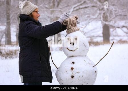 Duelmen, NRW, Allemagne. 17 janvier 2021. Un marcheur apporte une touche finale à un bonhomme de neige qui grince. Une couche de neige fraîche est tombée la nuit, transformant la campagne du Muensterland en un pays merveilleux pour l'hiver pendant quelques jours. Credit: Imagetraceur/Alamy Live News Banque D'Images