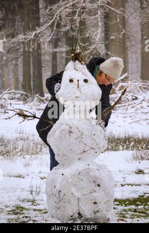 Duelmen, NRW, Allemagne. 17 janvier 2021. Un marcheur apporte une touche finale à un bonhomme de neige haut aux cheveux à pointes. Une couche de neige fraîche est tombée la nuit, transformant la campagne du Muensterland en un pays merveilleux pour l'hiver pendant quelques jours. Credit: Imagetraceur/Alamy Live News Banque D'Images