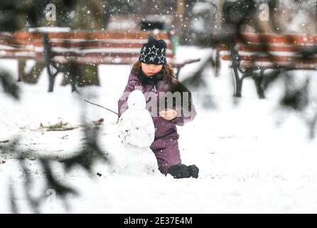 Francfort, Allemagne. 17 janvier 2021. Un enfant fait un bonhomme de neige dans un parc couvert de neige à Francfort, en Allemagne, le 17 janvier 2021. Une chute de neige a frappé Francfort dimanche. Crédit: Lu Yang/Xinhua/Alay Live News Banque D'Images