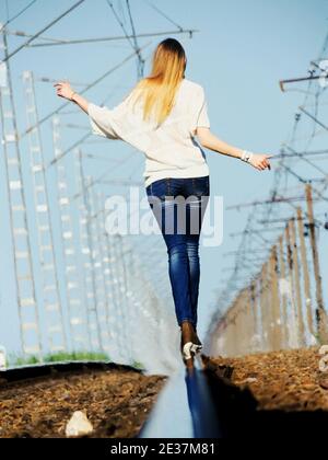 Une fille marche sur les rails du chemin de fer. Marche sur les voies. Banque D'Images