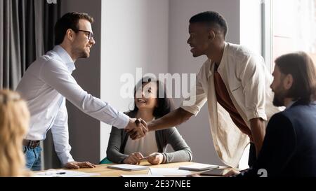 Souriant 30s homme d'affaires caucasien serrer la main avec un collègue africain. Banque D'Images