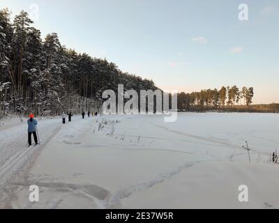 Paysage d'hiver : les skieurs longent un lac gelé par beau temps Banque D'Images