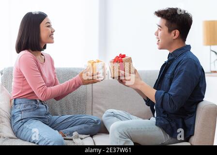 Un couple asiatique charmant offre des boîtes cadeaux célébrant les vacances à la maison Banque D'Images