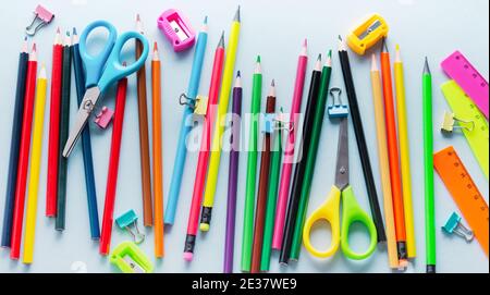 Crayons de couleur, ciseaux, bloc-notes, règle, stylo, gomme, taille-crayon et plus encore en verre. Papeterie pour l'école et le bureau sur fond bleu clair. Bannière. C Banque D'Images