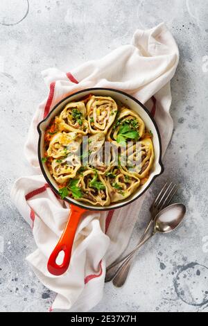 La pâte à viande roule avec de la viande ou des boulettes paresseuses dans une ancienne casserole en fonte rouge sur fond gris rustique. Vue de dessus. Banque D'Images