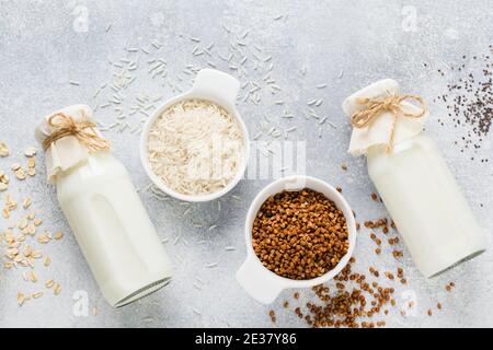 Régime alimentaire concept sain. Lait diététique végétarien à base de riz aux céréales, sarrasin et avoine, trois types de produits faits maison sur fond de tendance en béton gris. Copier sp Banque D'Images