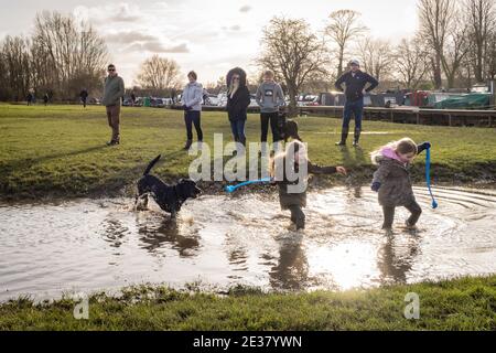 Oxford, Oxfordshire, Royaume-Uni. 17 janvier 2021. Les gens marchent à travers Port Meadow. Un laboratoire noir, Cooper chase une balle dans l'eau de Port Meadow, tandis que les enfants jouent dans la même sortie froide. Credit: Sidney Bruere/Alay Live News Banque D'Images