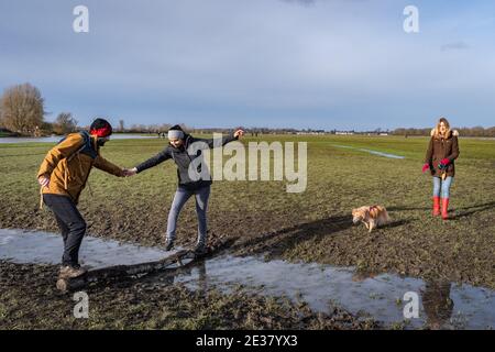 Oxford, Oxfordshire, Royaume-Uni. 17 janvier 2021. Les gens marchent à travers Port Meadow. Une femme marche son chien de mélange de spaniels, Roxie, à travers un pré boueux par une journée ensoleillée. Port Meadow est un terrain ouvert de 900 hectares à Oxford. Credit: Sidney Bruere/Alay Live News Banque D'Images