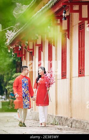 Couple dans des robes vietnamiennes traditionnelles marchant dehors après avoir fêté le chinois Nouvelle année Banque D'Images