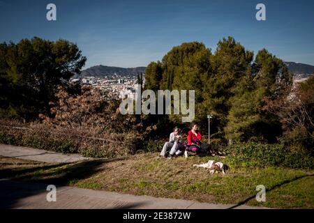 Barcelone, Catalogne, Espagne, le 17 janvier 2021 : en ce dimanche ensoleillé, les femmes et un chien se détendent sur la colline de Montjuic avec la ville de Barcelone en arrière-plan, a imposé un confinement municipal pour lutter contre la propagation du coronavirus troisième vague dans la région catalane interdit aux gens de quitter sa propre ville ou ville limites. Credit: Jordi Boixareu/Alamy Live News Banque D'Images