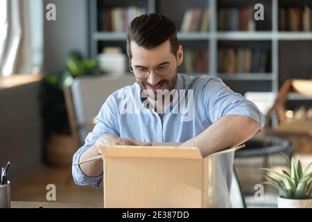 Curieux jeune homme dans des lunettes de déballage énorme boîte en carton. Banque D'Images