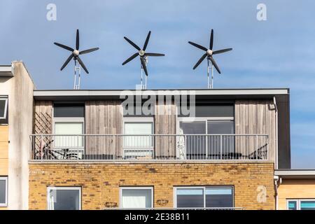 Trois petites éoliennes sur le toit d'un bloc d'appartements ou d'appartements résidentiels, Royaume-Uni. Énergie durable, durabilité. Banque D'Images