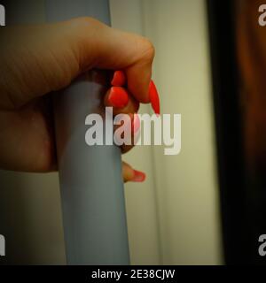 Une main d'une femelle avec un vernis à ongles rouge Pour obtenir de l'aide sur un train de métro à Londres Banque D'Images