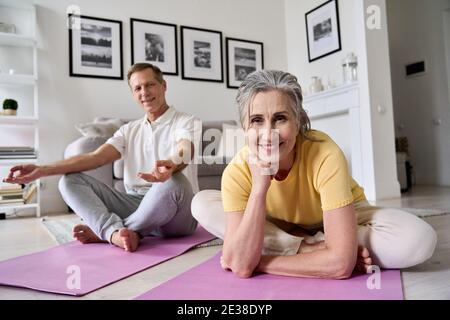 Bonne tenue femme d'âge moyen s'exerçant avec son mari à la maison, portrait. Banque D'Images