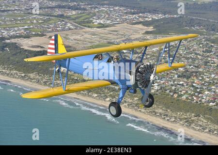 Un Boeing N2S Staarman des années 1940 en biplan aux couleurs de l'armée américaine, utilisant la fumée d'affichage. Banque D'Images