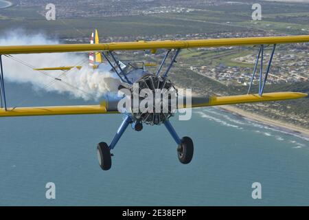 Un Boeing N2S Staarman des années 1940 en biplan aux couleurs de l'armée américaine, utilisant la fumée d'affichage. Banque D'Images