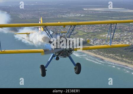 Un Boeing N2S Staarman des années 1940 en biplan aux couleurs de l'armée américaine, utilisant la fumée d'affichage. Banque D'Images