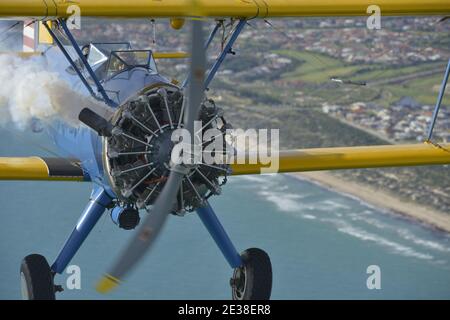 Un Boeing N2S Staarman des années 1940 en biplan aux couleurs de l'armée américaine, utilisant la fumée d'affichage. Banque D'Images