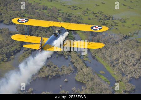 Un Boeing N2S Staarman des années 1940 en biplan aux couleurs de l'armée américaine, utilisant la fumée d'affichage. Banque D'Images