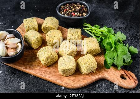 Billes de falafel brutes sur une planche à découper en bois. Arrière-plan noir. Vue de dessus Banque D'Images