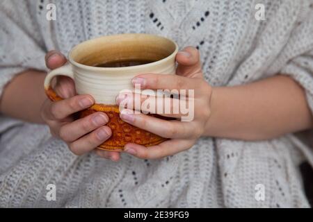 Jeune femme tenant une tasse de thé. Week-end d'automne ou d'hiver moody. Journée paresseuse, quarantaine, séjour à la maison, scène chaleureuse, concept d'hygge. Banque D'Images
