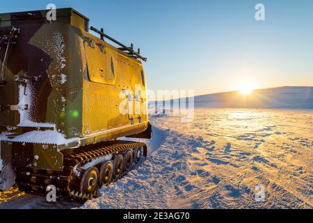 chasse-neige sur une plaine enneigée au coucher du soleil. Un camion à neige nettoie la neige de la route et des rues au coucher du soleil Banque D'Images