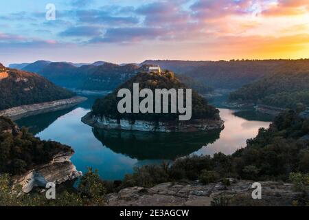 Paysage de rivière au coucher ou au lever du soleil. Monastère religieux isolé en solitude au sommet d'une montagne. Sant Pere de Casserres, Riu Ter, Sau Rese Banque D'Images