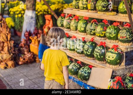 Un petit garçon visite les Watermelons avec une gravure festive sur Tet Eve. Tet est le nouvel an lunaire et célébré pendant quatre jours au Vietnam Banque D'Images