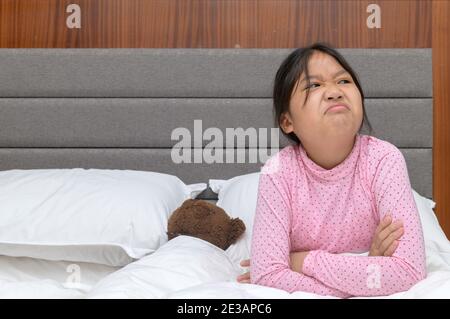 Fille en colère assise sur le lit et touchy dans la chambre, bouleversé et agacé concept d'émotion Banque D'Images