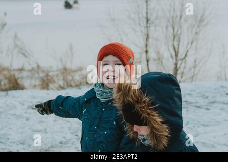 enfants jouant avec la neige. les enfants regardent le paysage d'hiver. Les enfants regardent la mer d'hiver. Promenade en hiver au bord de la mer. Promenades en hiver avec les enfants Banque D'Images