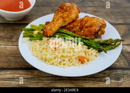 Pilons de poulet grillés avec riz, asperges et sauce Buffalo. Banque D'Images