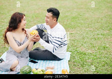 Un jeune couple heureux qui apprécie les oranges fraîches et juteuses lorsqu'il est romantique Pique-nique dans le parc le jour de la Saint-Valentin Banque D'Images