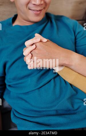Jeune homme souriant tenant la main de son ami lorsqu'ils On se détend au lit le dimanche matin Banque D'Images